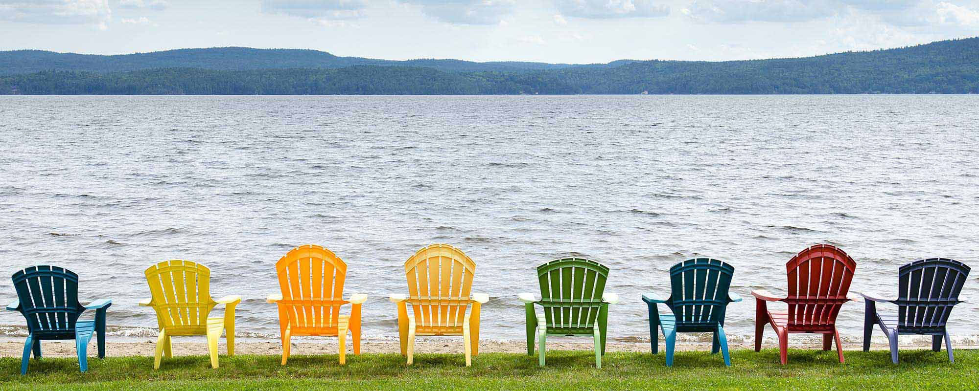 multicolored chairs lined up beside a body of water